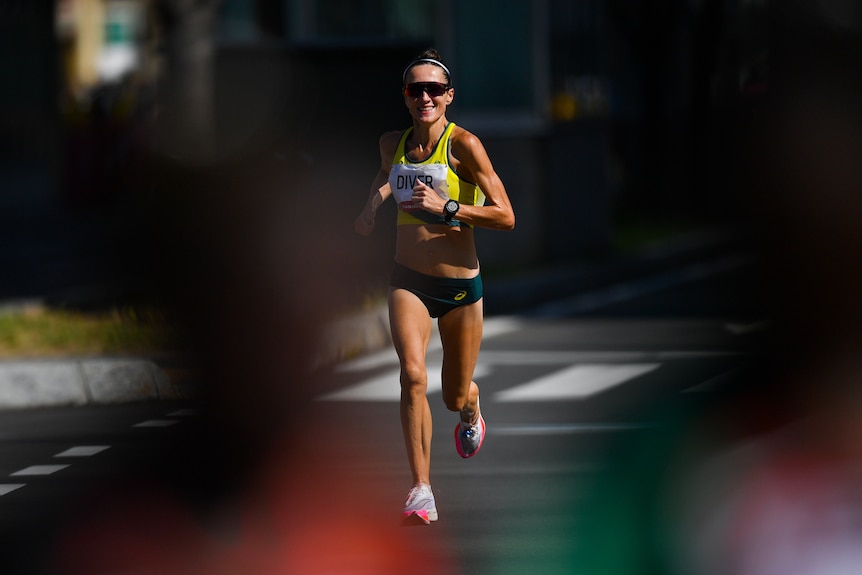 An Australian athlete smiles as she runs along the road through Sapporo in the women's marathon at the Olympics.