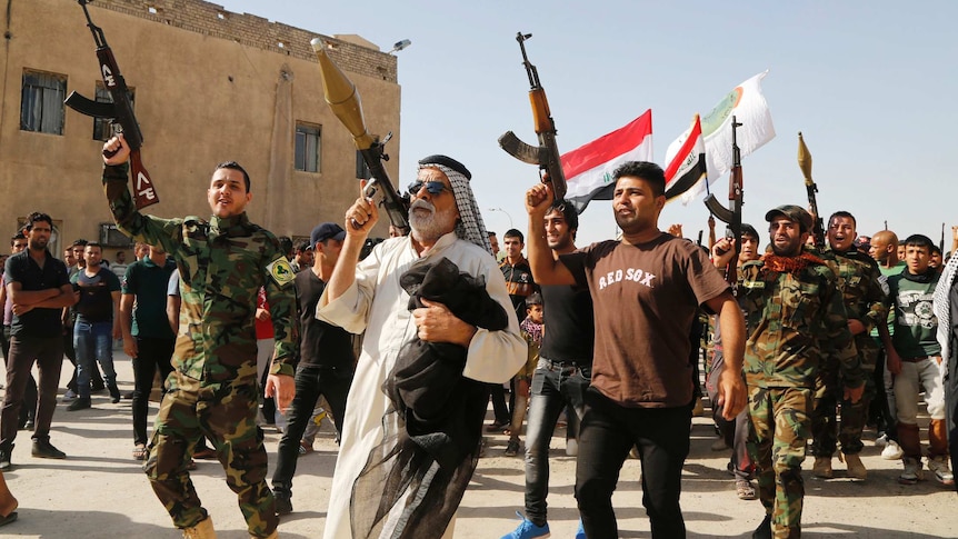 Iraqi army volunteers carry weapons during a parade on the streets of Baghdad