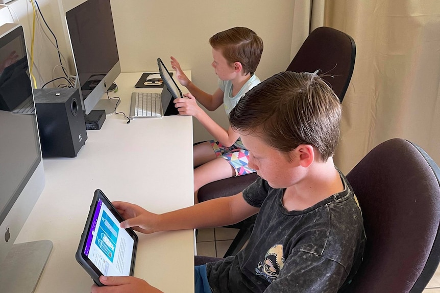 Two boys work on computers.