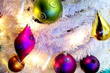 Bright coloured Christmas decorations on a white tree.