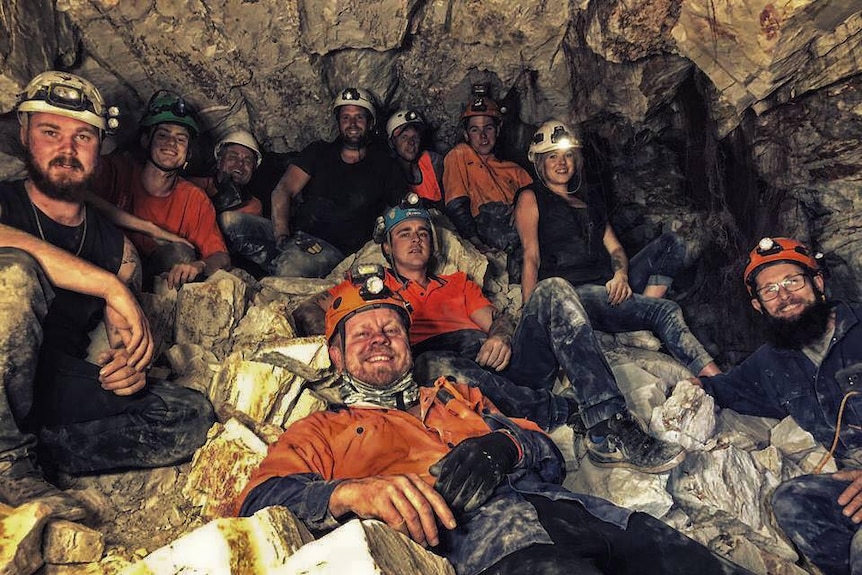 a group of men and women pose for a photo in an underground mine.
