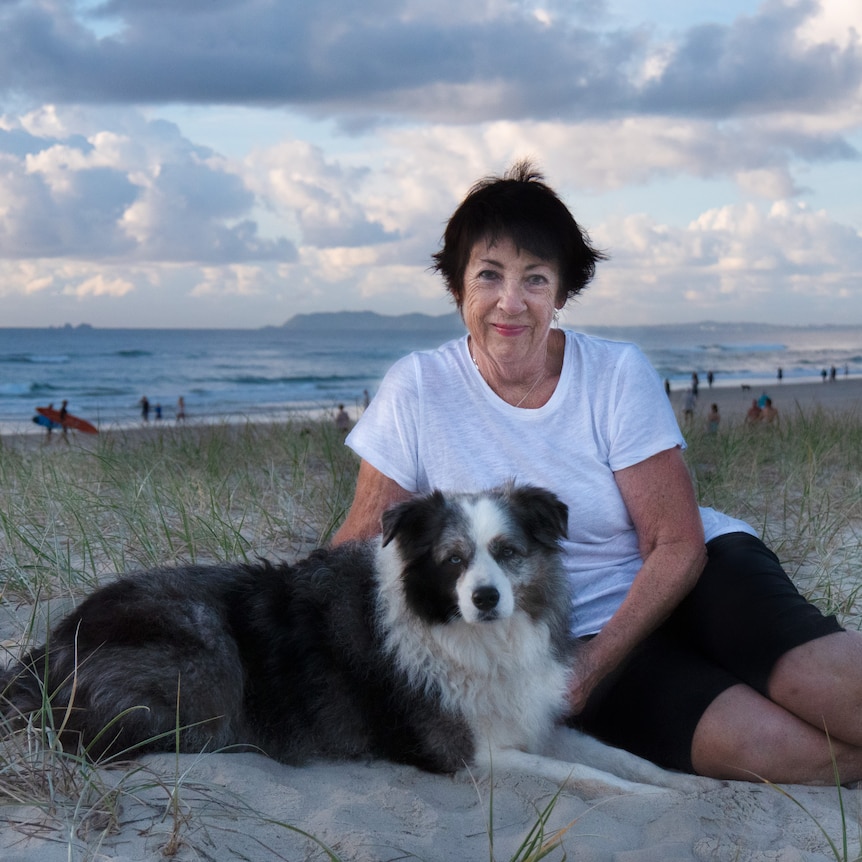 Angela Catterns sitting on a beach with a dog.
