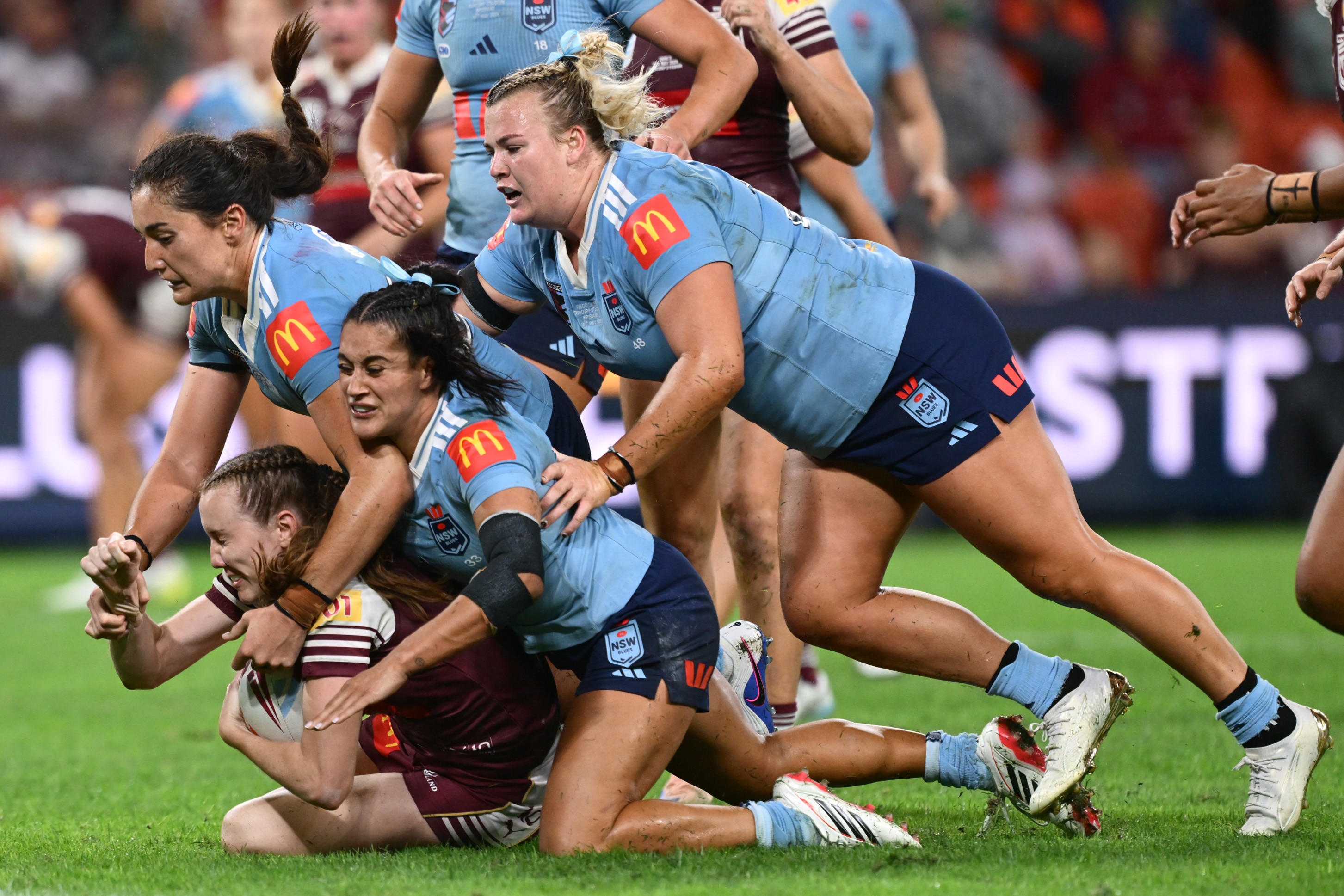 Three players tackle an opponent during a rugby league match