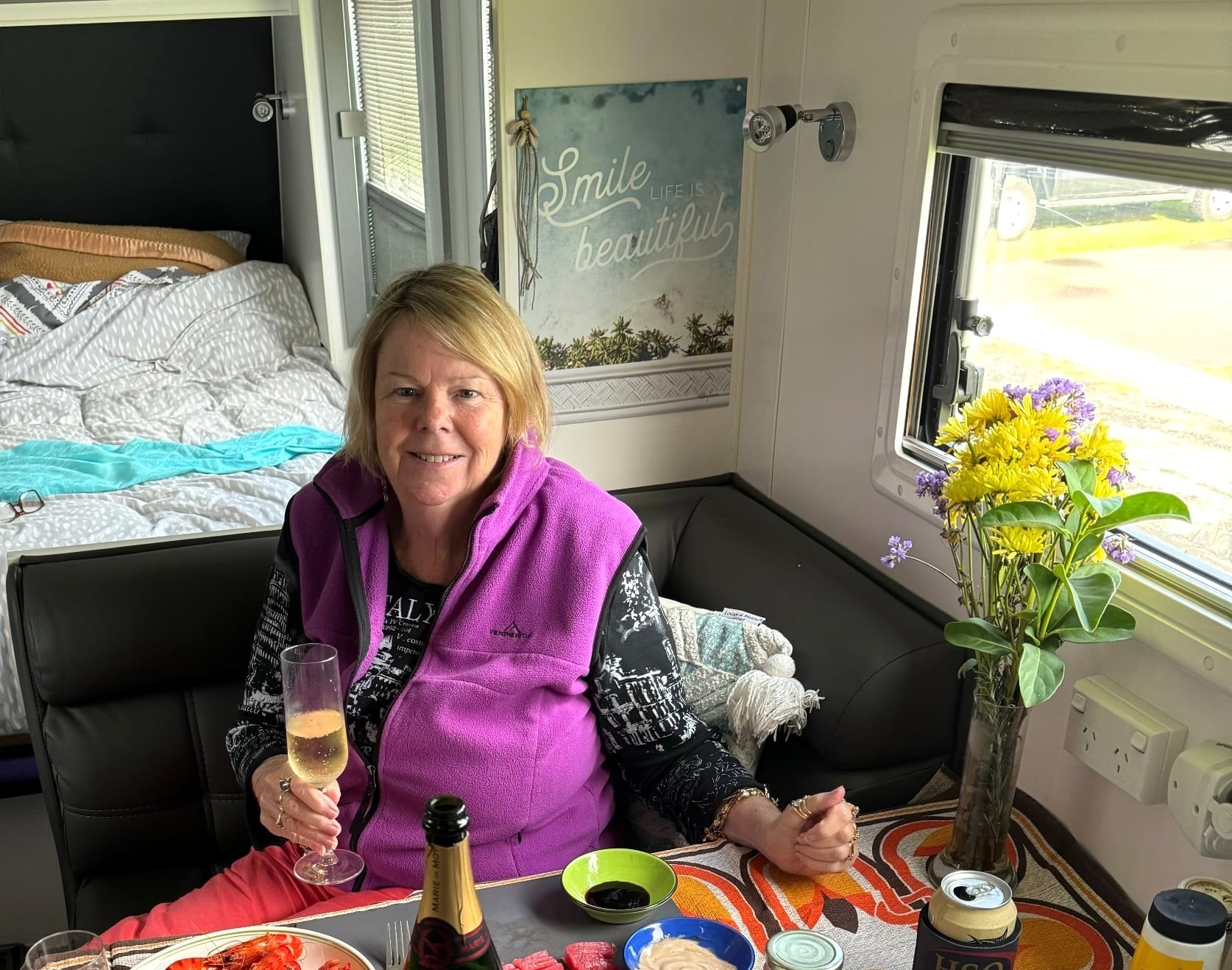 A woman holding a glass of champagne inside a caravan.