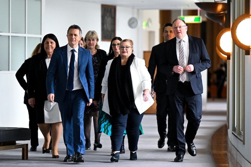 Un groupe d'hommes et de femmes marche dans un couloir.