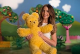 A woman holds a big yellow teddy bear