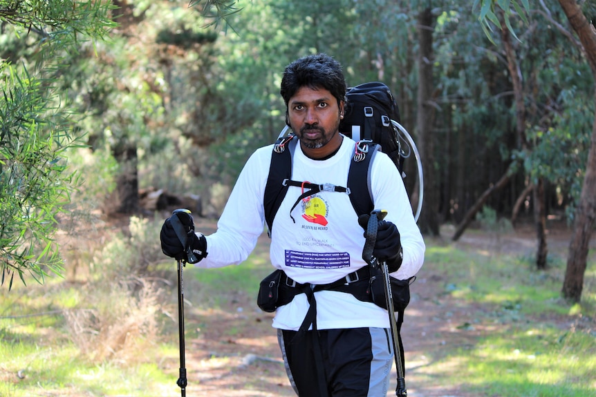 A man with a large backpack and walking sticks