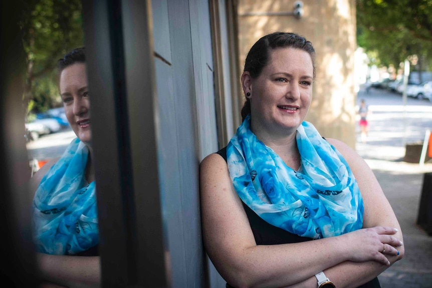 Katrina Munting, a survivor of sexual abuse, crosses her arms as she poses for a photo