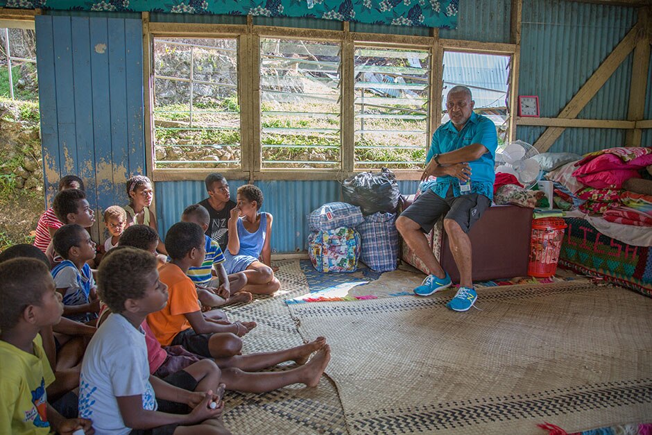 Fiji Prime Minister sits and talks to children sitting on the floor