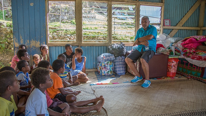 Fiji Prime Minister sits and talks to children sitting on the floor