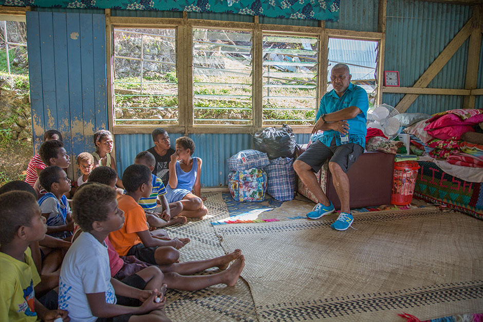 Fiji Prime Minister sits and talks to children sitting on the floor