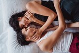 Two women lay in bed looking at one another in a story about ways to improve your sex life today.