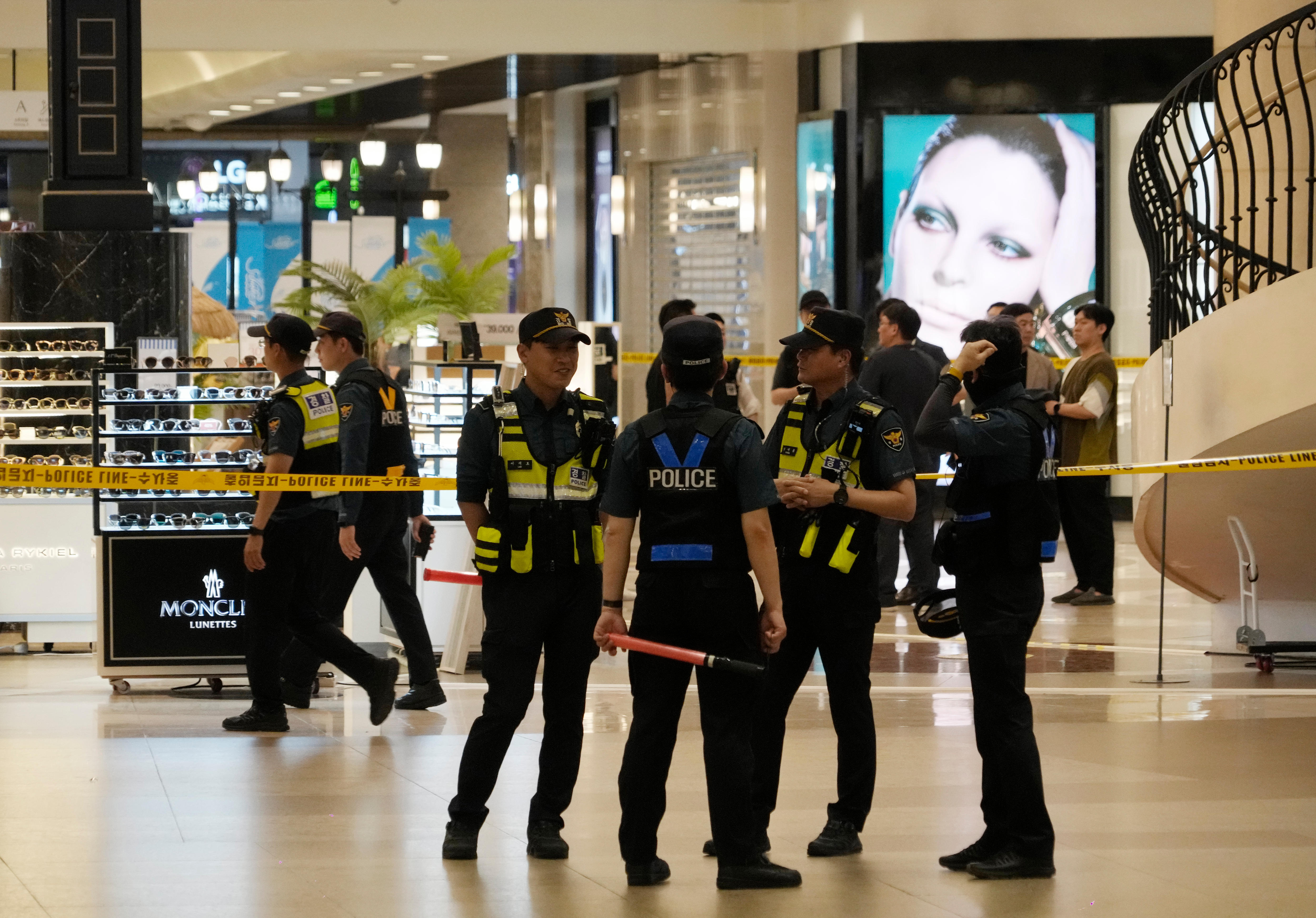 Uniformed police officers cordon off a crime scene near shops inside a mall at a large subway station.