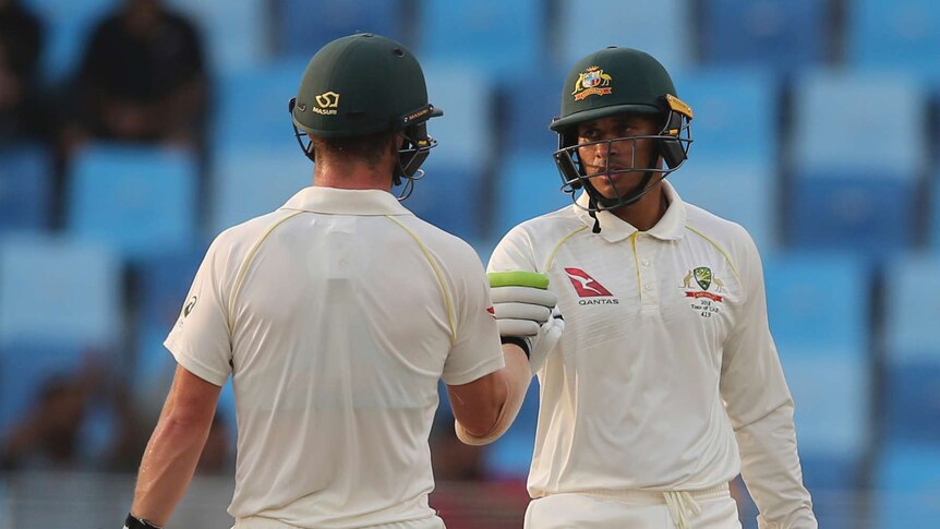 Usman Khawaja and Travis Head bump gloves