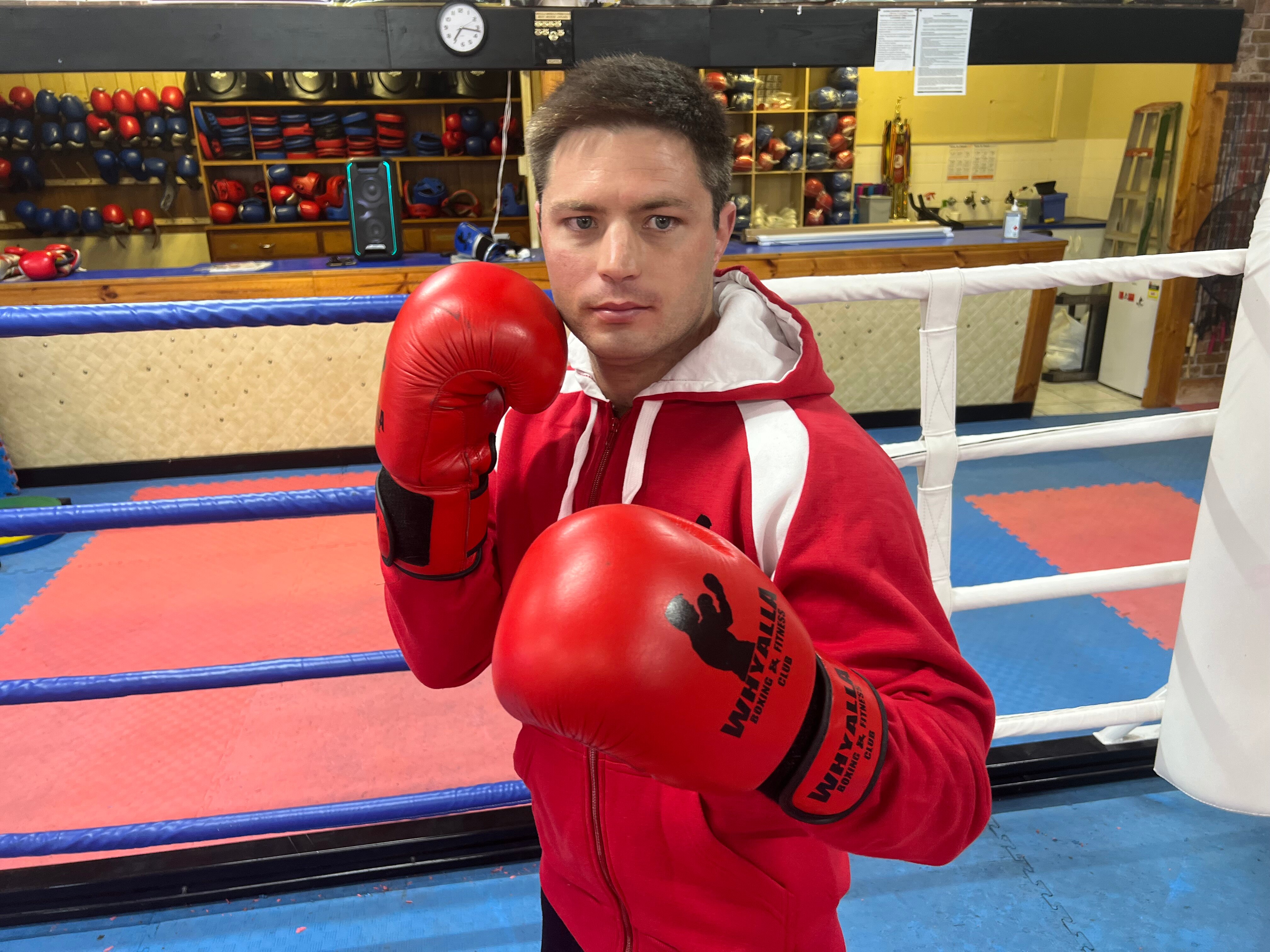 A man wearing boxing gloves looks at the camera. 