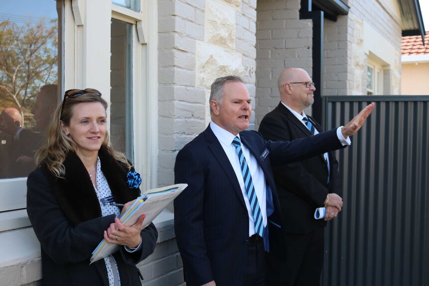 An auctioneer and his helpers auctioning a house auction in Adelaide