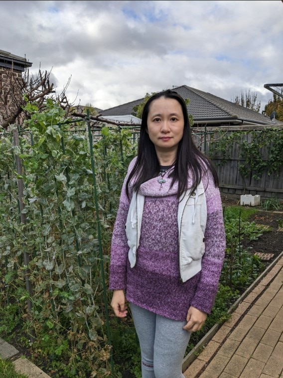 Woman wearing a lavender jumper standing in a garden