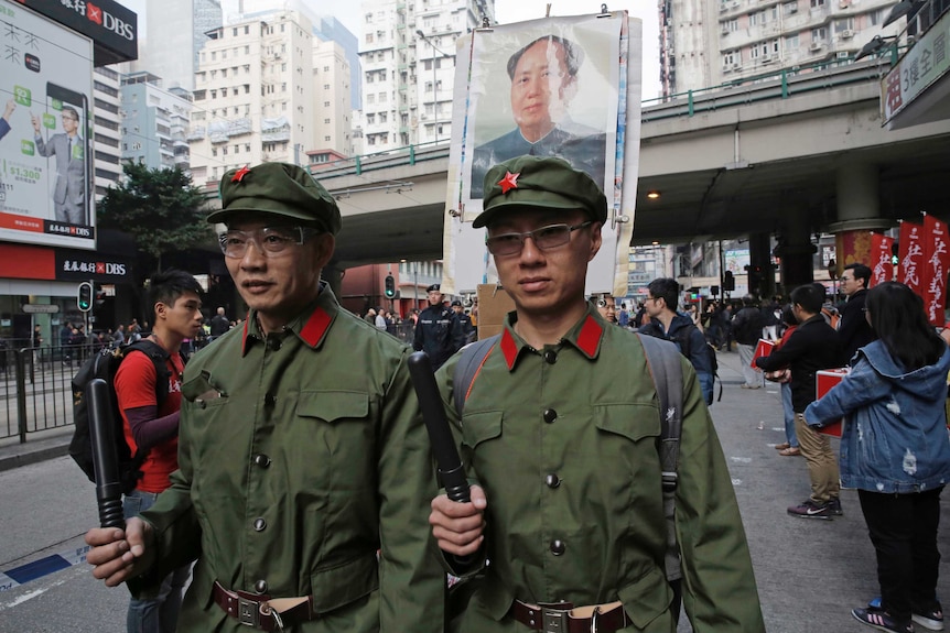 Two men dressed as Chinese soldiers stand on the road.