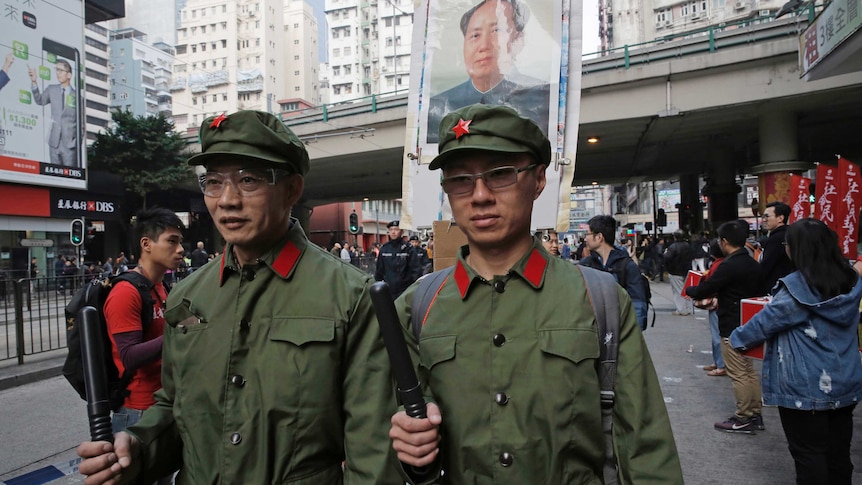 Two men dressed as Chinese soldiers stand on the road.