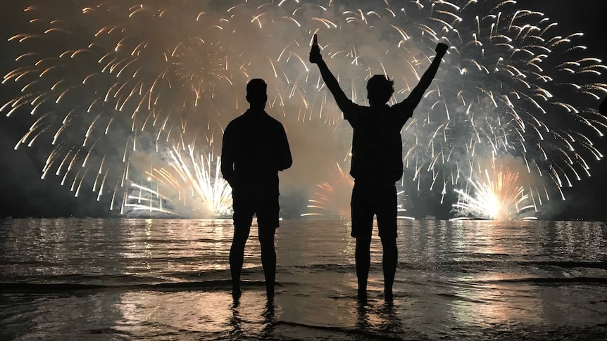 Two men in silhouette watch fireworks explode over Darwin