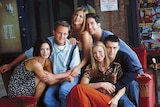 A file phot of the cast of the hit television series Friends sitting on a red couch.