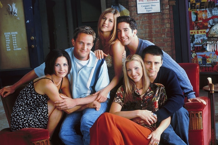A file phot of the cast of the hit television series Friends sitting on a red couch.