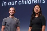 Mark Zuckerberg and Priscilla Chan stand in front of a screen saying "Can we cure all diseases in our children's lifetime?"