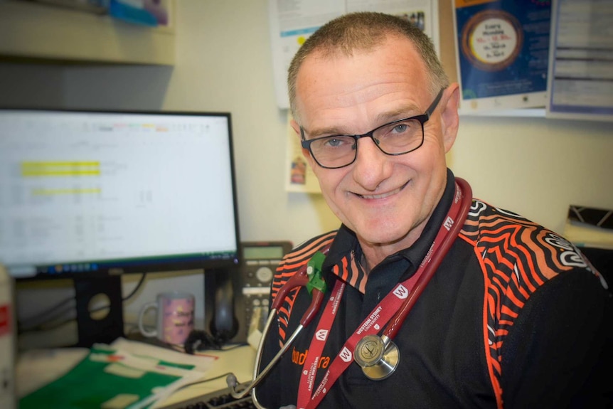 Middle aged man waering glasses sitting in office.