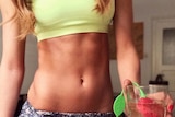 A woman in workout gear stands next to a detox tea product.