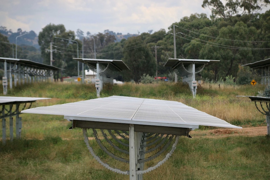 Large solar panels sit out in a field on an overcast day