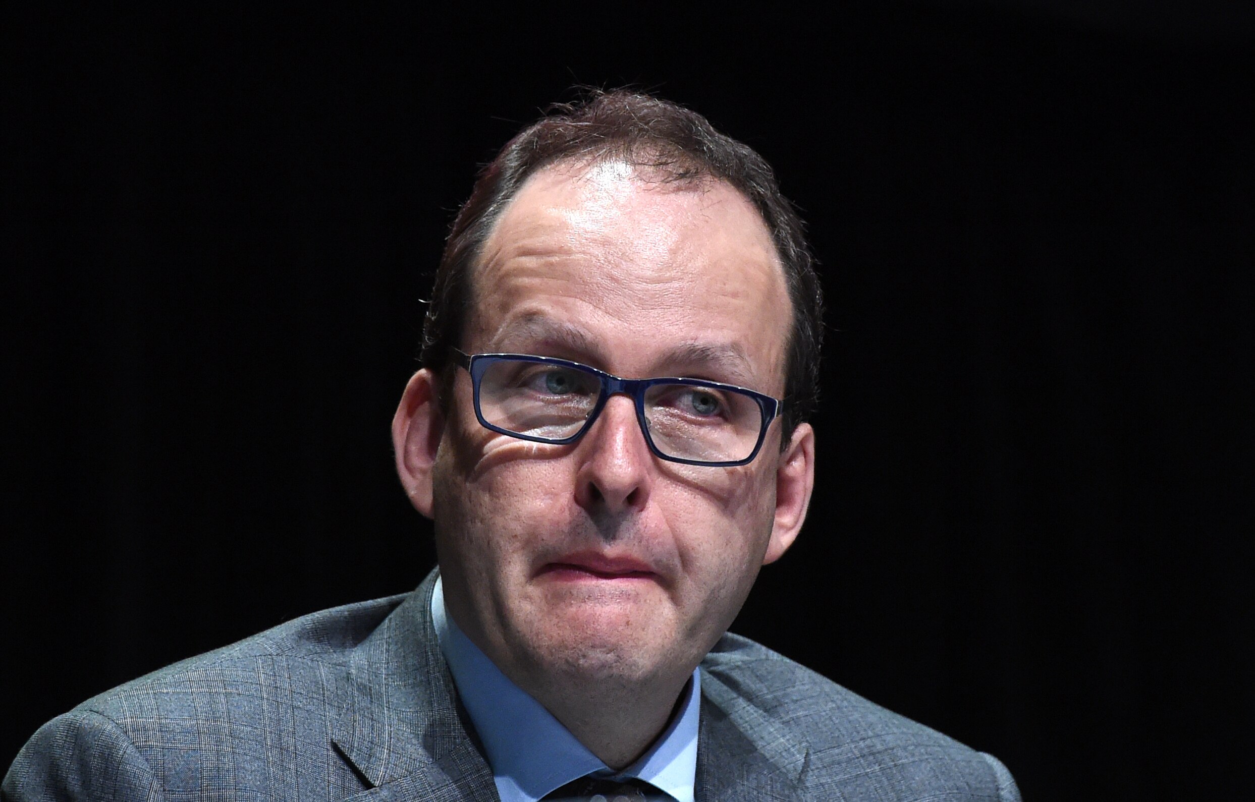 a man wearing glasses at a meeting