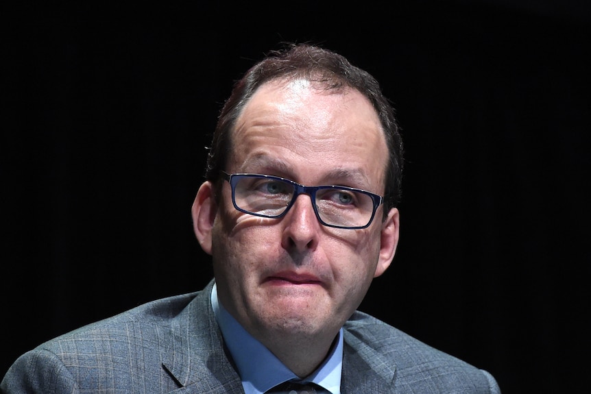 a man wearing glasses at a meeting