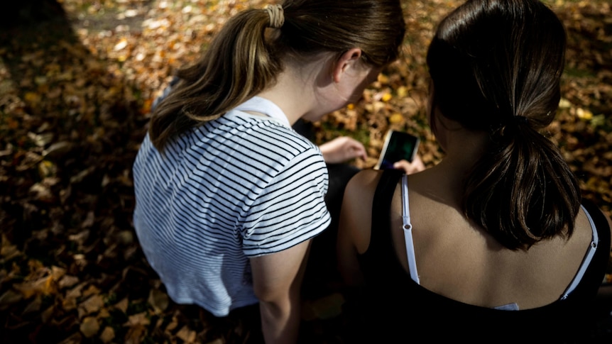 Two girls looking at the screen of a smart phone