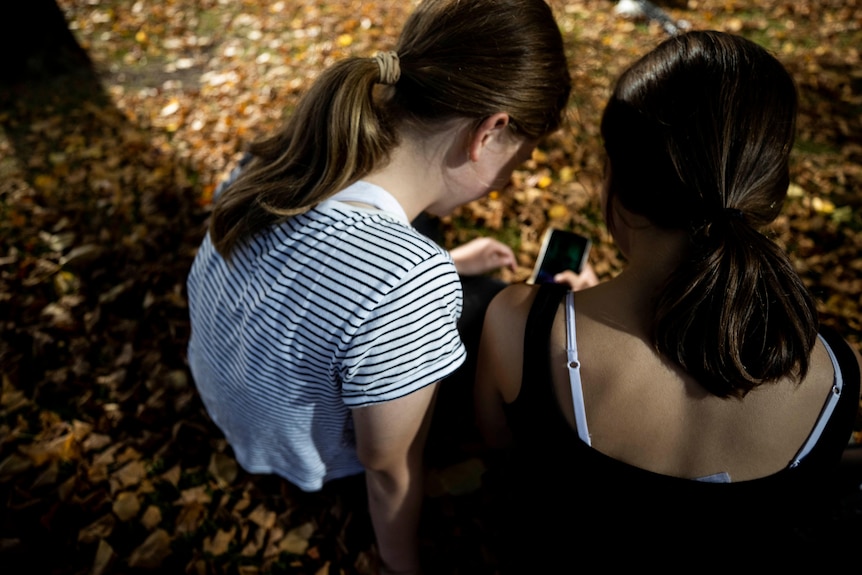 Two girls looking at the screen of a smart phone