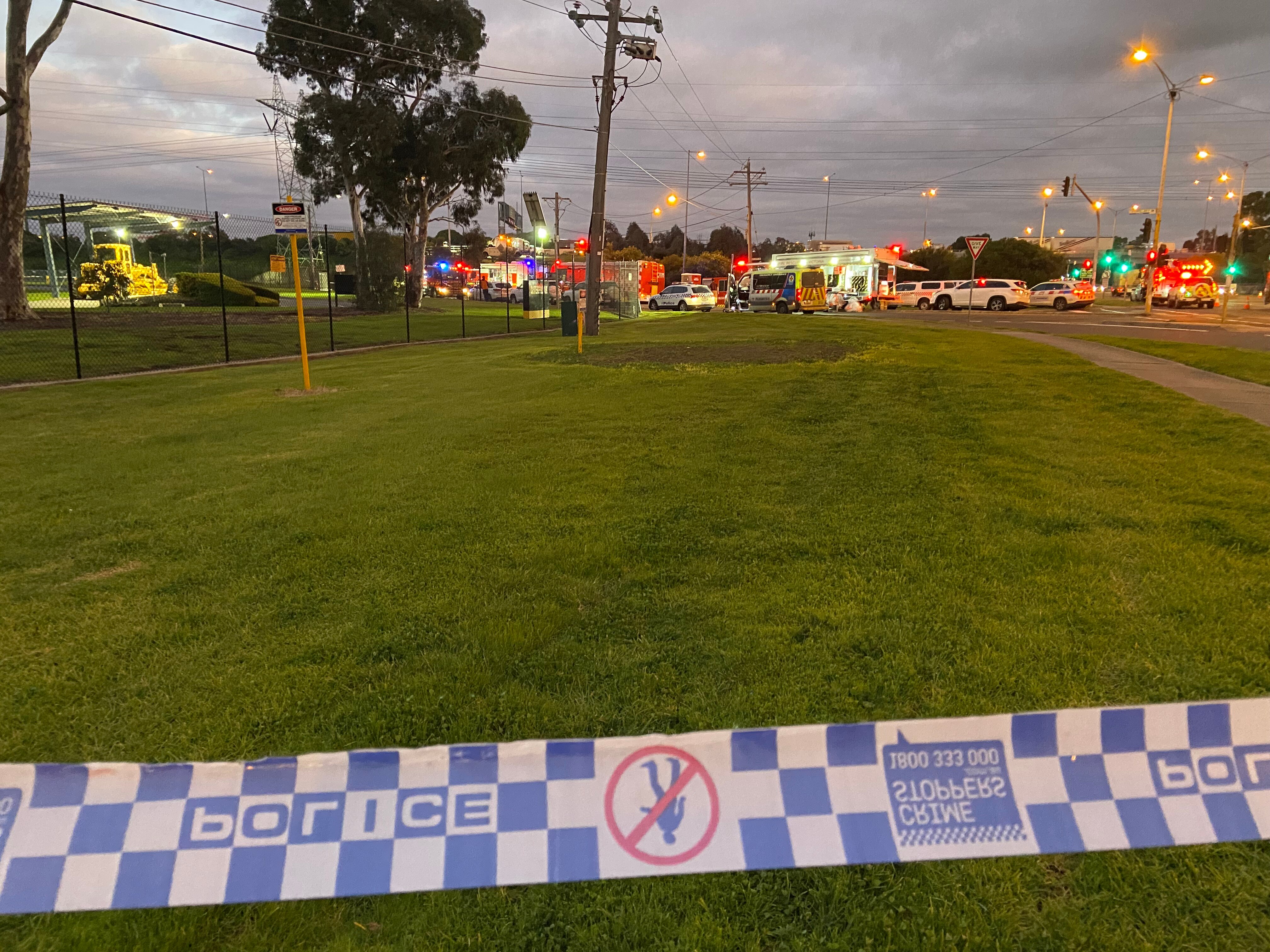 Emergency services behind police tape at dawn.