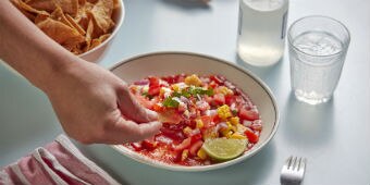 A bowl of salad salsa with chopped tomato, corn and red onion, served with tortilla chips for an easy summer dinner or snack.