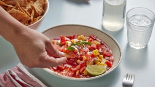 A bowl of salad salsa with chopped tomato, corn and red onion, served with tortilla chips for an easy summer dinner or snack.