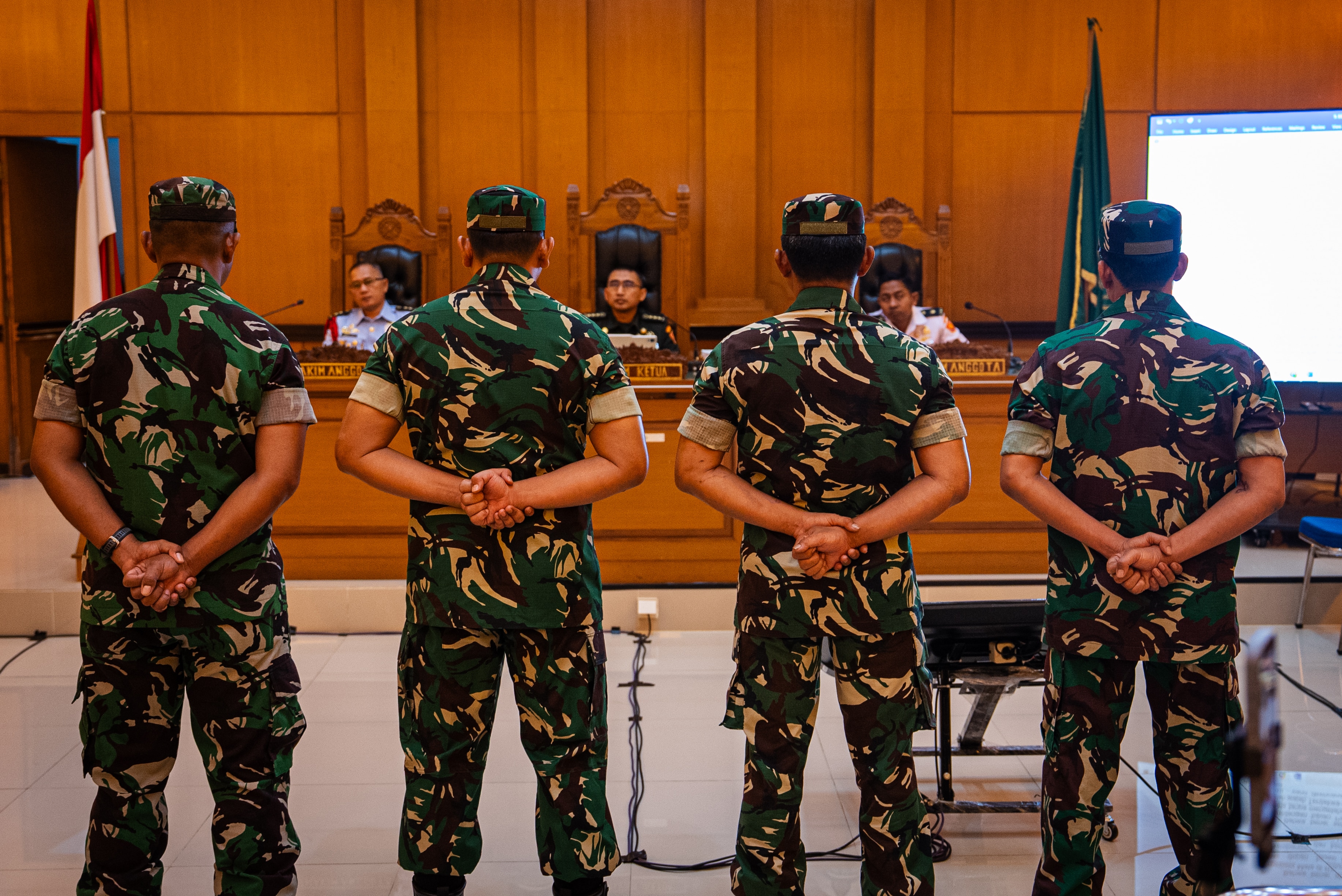 Four men dressed in military fatigues line up in front of a judge in Jakarta