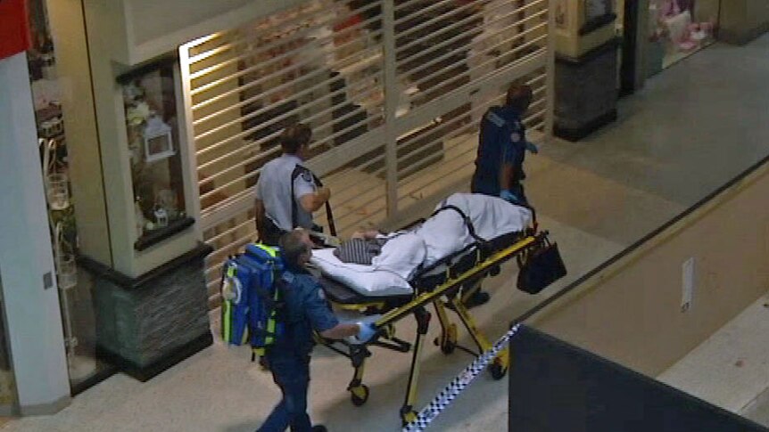 A victim of a shooting is wheeled out of the Robina Town Centre shopping centre.