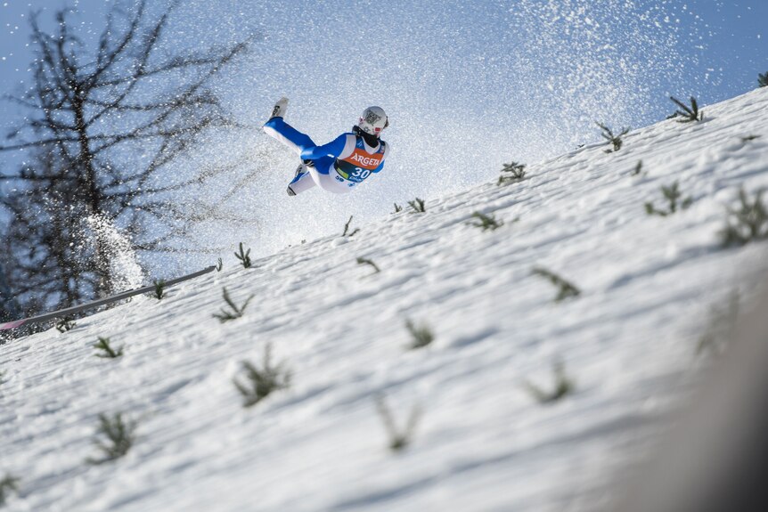 Daniel Andra Tande bounces on his back with his skis in front of him