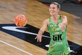 Courtney Bruce flicks the ball to a teammate. It is Indigenous Round and she is wearing a green dress with Indigenous designs.
