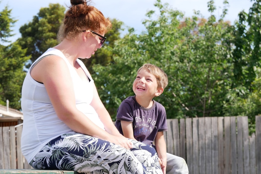 A young boys looks up and smiles at his mother