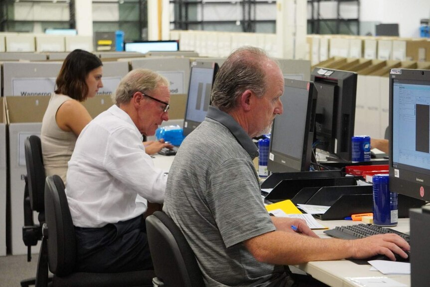 A row of Electoral Commission staff at computers working.