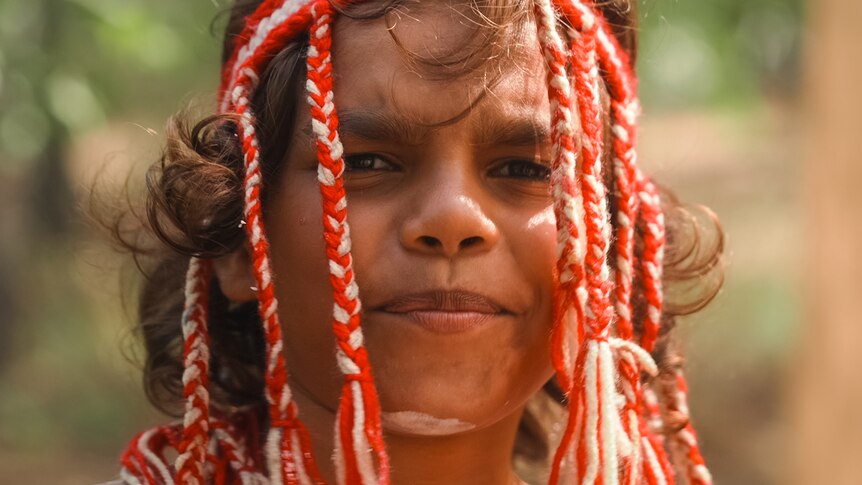 A young Indigenous person in ceremonial headwear and face paint.