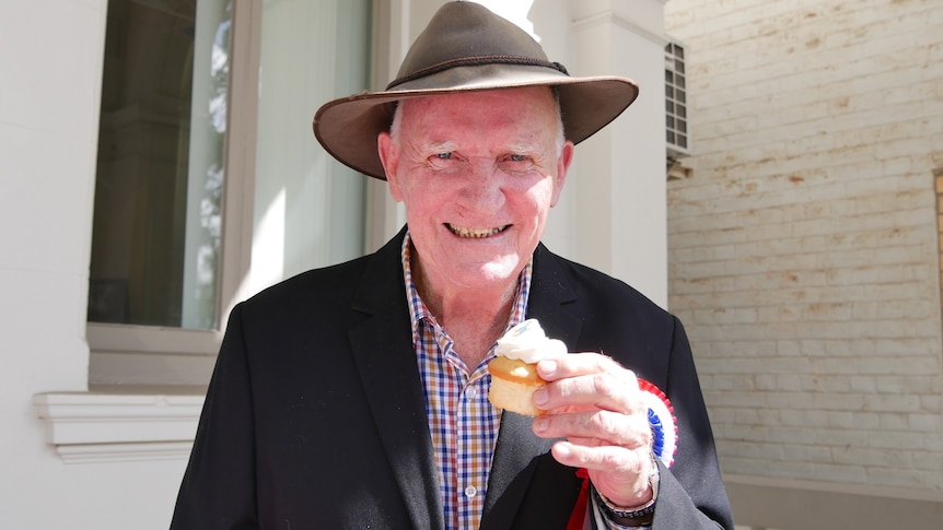 Tom Wyatt, wearing a battered akubra, holds a cupcake up to the camera