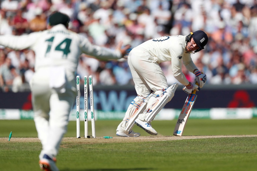 Jason Roy looks back at his broken stumps while completing an unsuccessful shot. And Australian celebrates in the foreground.