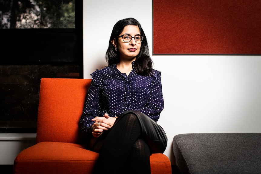 Sukhmani Khorana sits on a red couch.