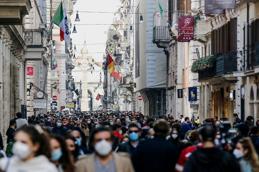 a crowd of people in a street in Rome during the day wearing face masks