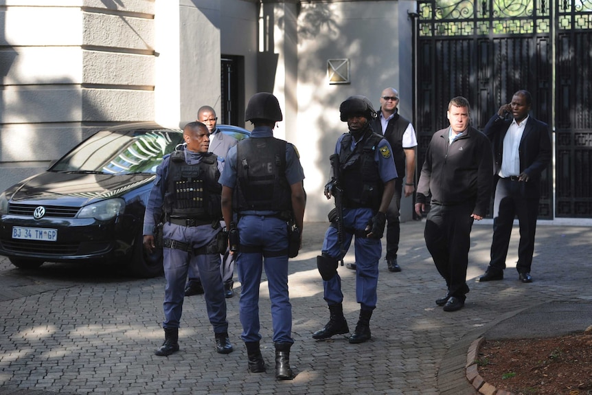 South African police stand in front of gates to a home in Johannesburg.