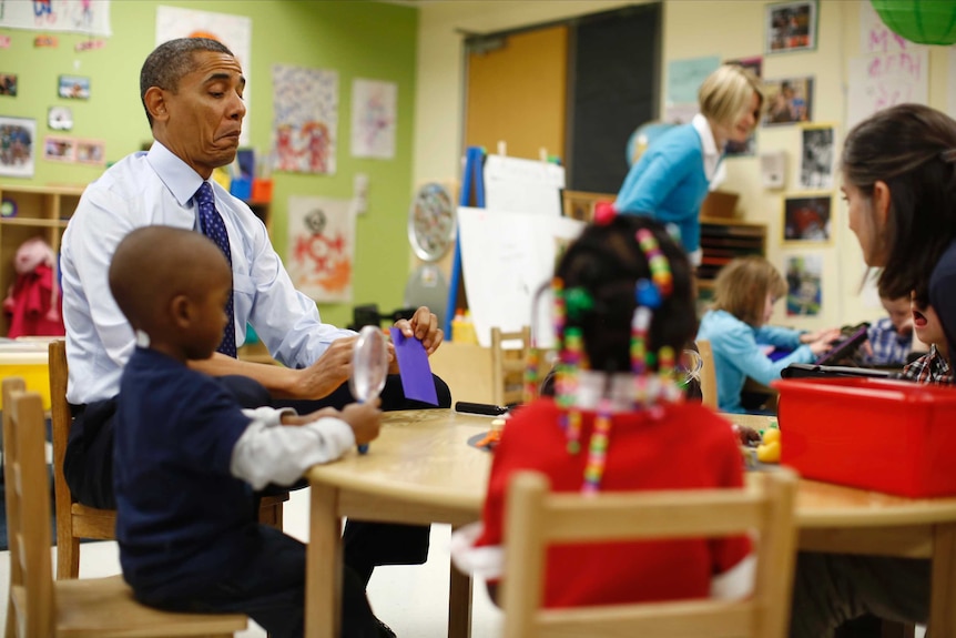 Barack Obama reads a card during a game with children.